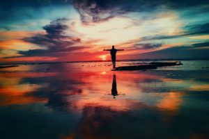 man with arms outstretched looking into sunset